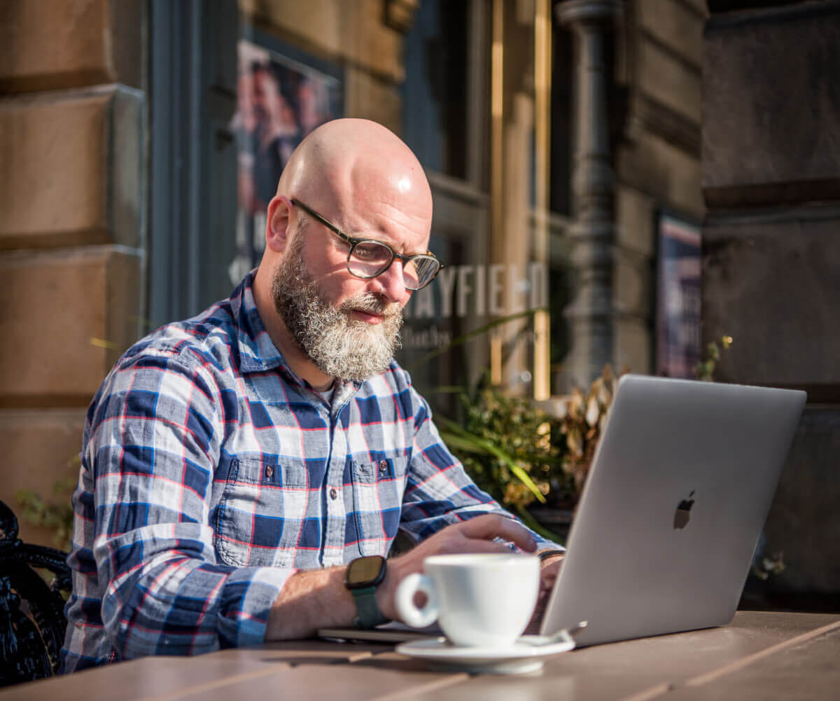 André working at his laptop in a coffee shop.